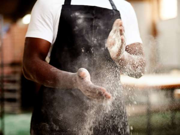Chef with flour on his hands making a pizza. 