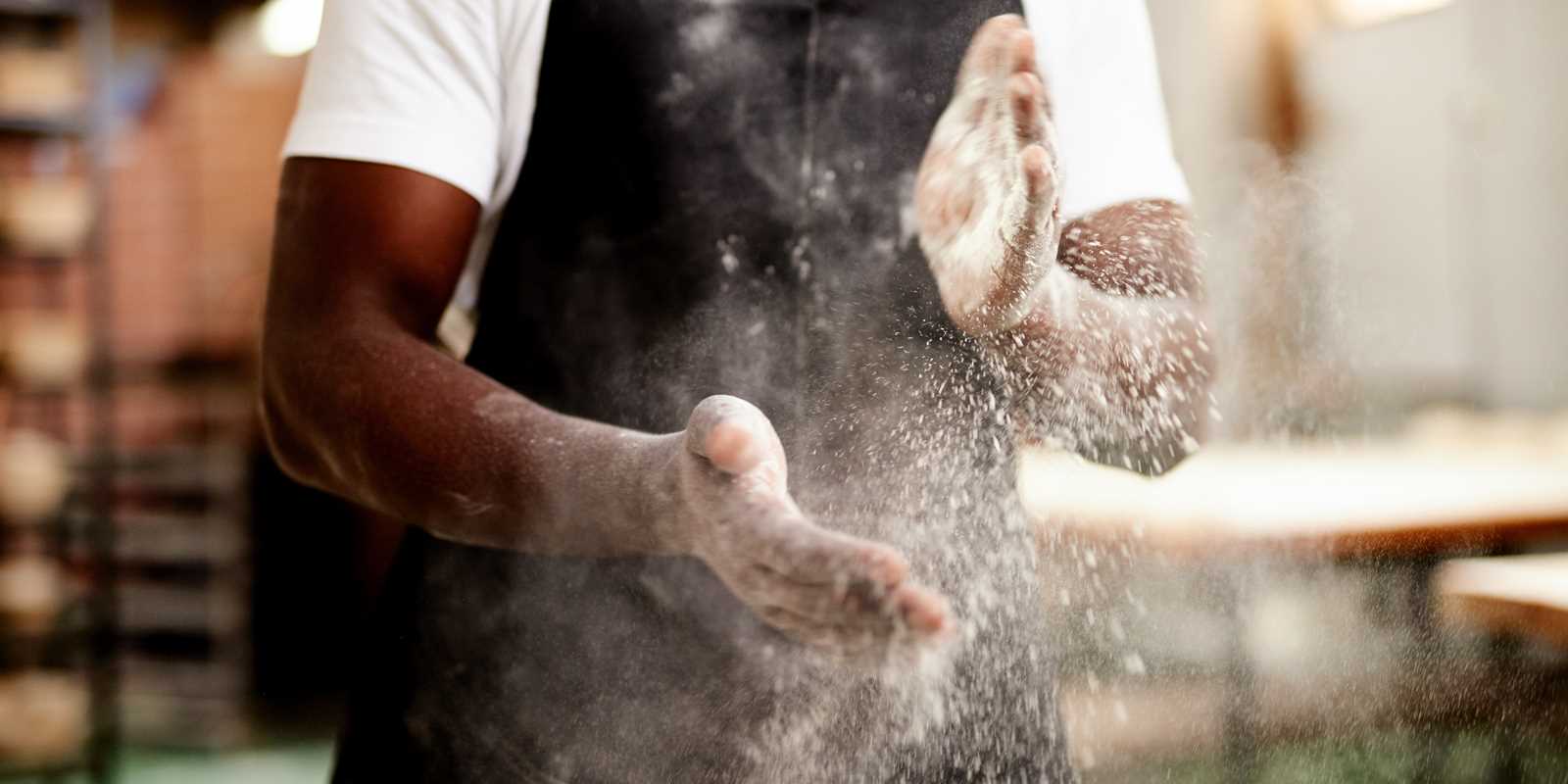 Chef with flour on his hands making a pizza. 