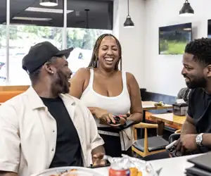 Patrons of Black Pizza chatting and laughing while enjoying pizza. 