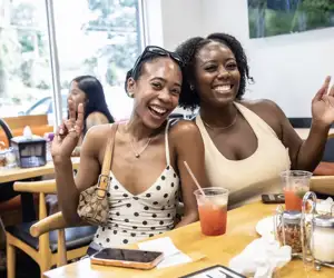 Two friends smiling at Black Pizza as they wait to enjoy a meal. 